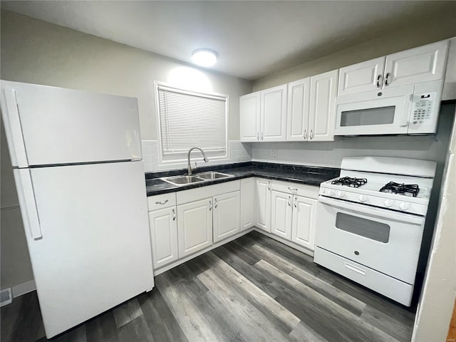 kitchen featuring white appliances, dark countertops, dark wood-style floors, white cabinetry, and a sink