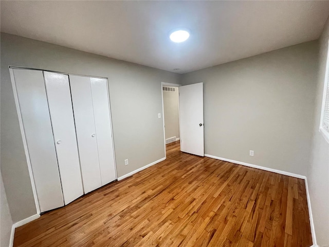 unfurnished bedroom with a closet, baseboards, visible vents, and light wood finished floors