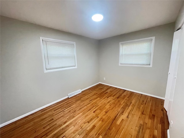 empty room with baseboards, visible vents, and wood finished floors