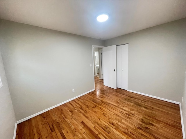 unfurnished bedroom featuring a closet, baseboards, and wood finished floors