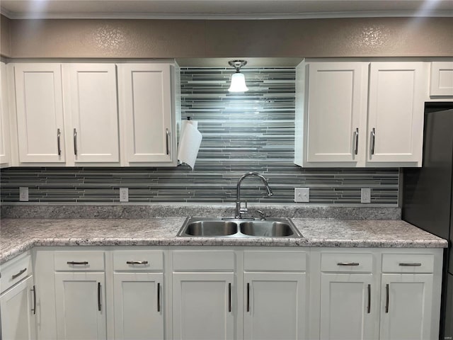 kitchen with freestanding refrigerator, white cabinetry, a sink, and decorative backsplash