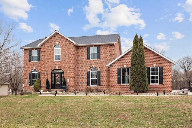 colonial house with brick siding, roof with shingles, and a front yard