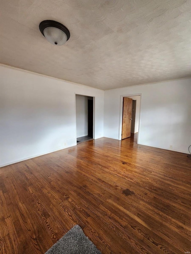 empty room featuring dark hardwood / wood-style floors and a textured ceiling