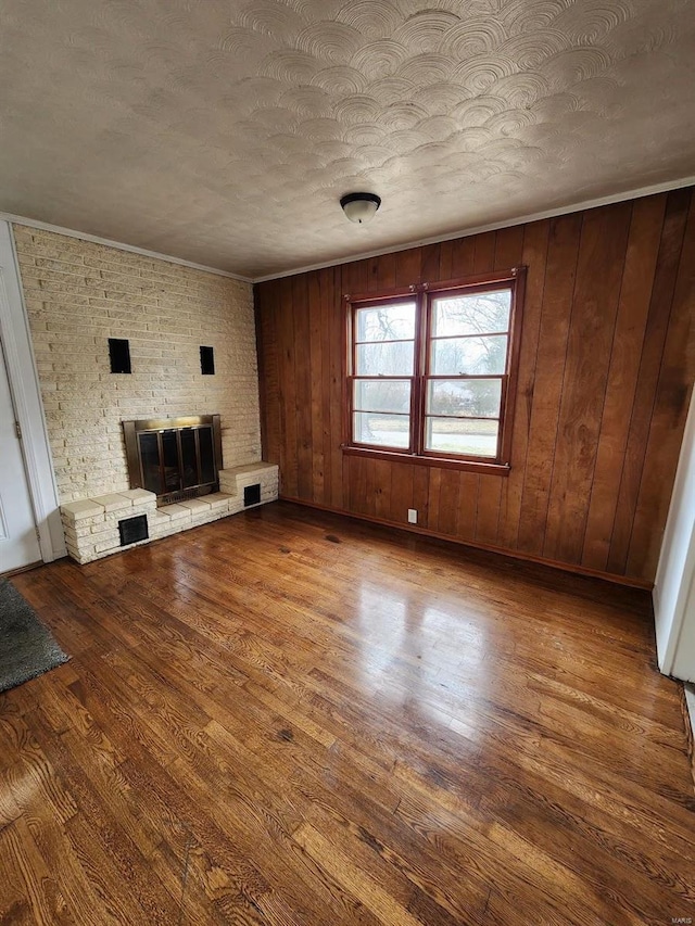 unfurnished living room featuring hardwood / wood-style flooring, a large fireplace, and a textured ceiling