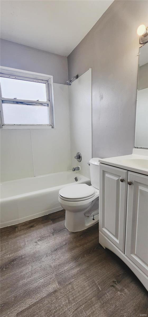 full bath with vanity, bathing tub / shower combination, wood finished floors, and toilet