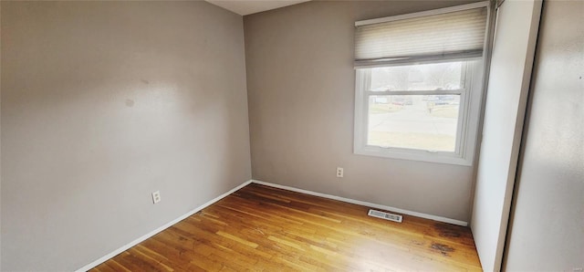 spare room with visible vents, baseboards, and wood finished floors
