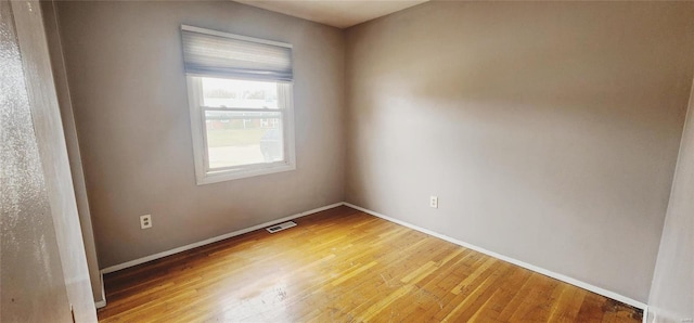 empty room featuring light wood finished floors, visible vents, and baseboards