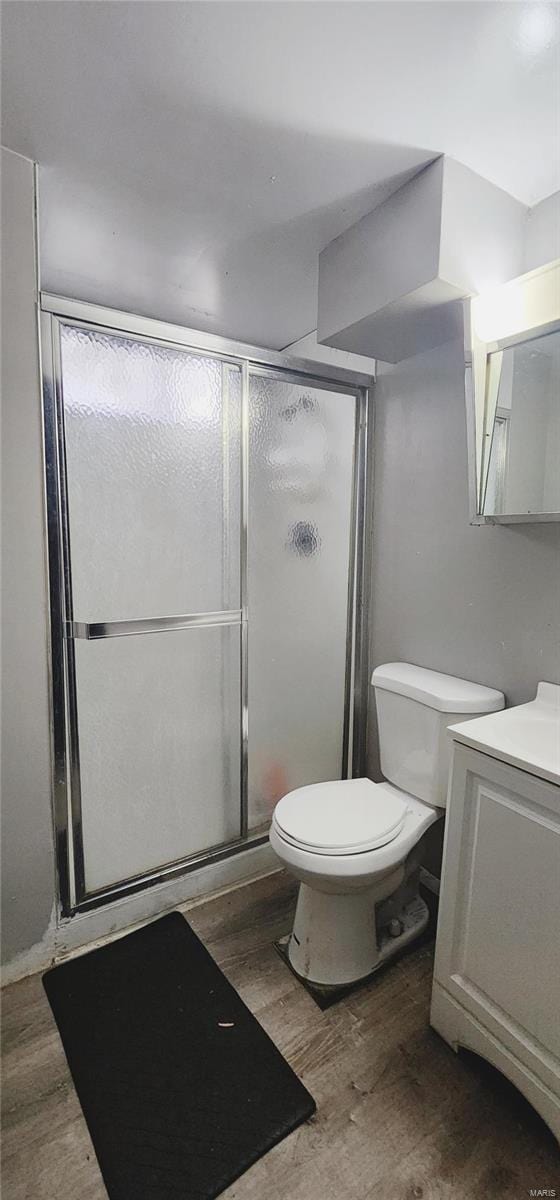 bathroom featuring a stall shower, vanity, toilet, and wood finished floors