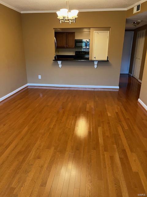 kitchen with pendant lighting, a notable chandelier, crown molding, and wood-type flooring