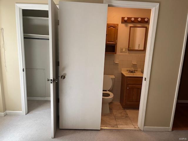 bathroom featuring tile patterned floors, vanity, toilet, and tile walls