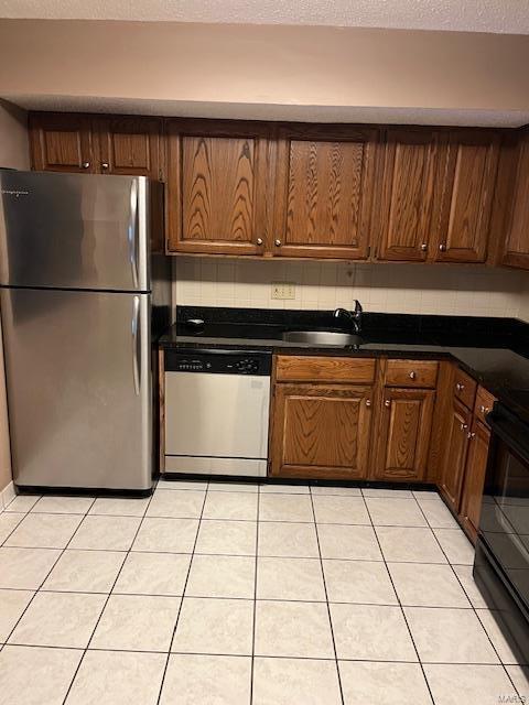 kitchen featuring sink, light tile patterned floors, backsplash, and appliances with stainless steel finishes