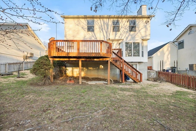 back of property featuring a chimney, a lawn, a fenced backyard, a wooden deck, and stairs