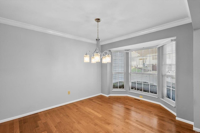 unfurnished dining area with an inviting chandelier, crown molding, baseboards, and wood finished floors