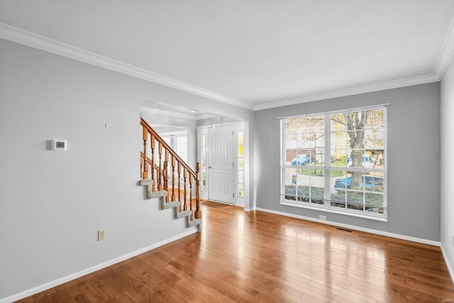 foyer with ornamental molding, stairway, baseboards, and hardwood / wood-style flooring