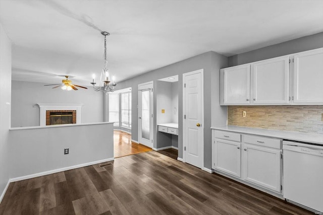 kitchen with white dishwasher, dark wood-style flooring, a fireplace, light countertops, and backsplash