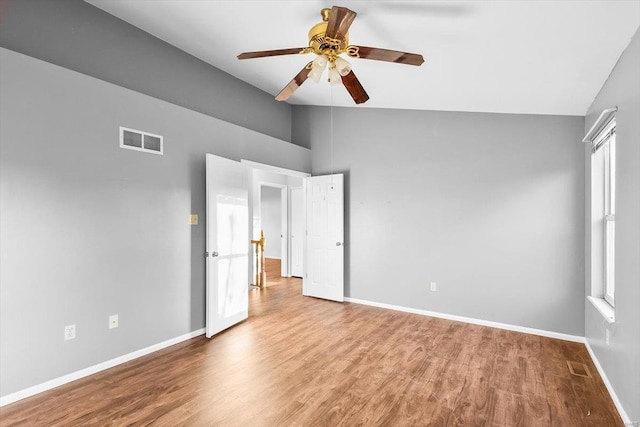 unfurnished bedroom featuring visible vents, vaulted ceiling, baseboards, and wood finished floors