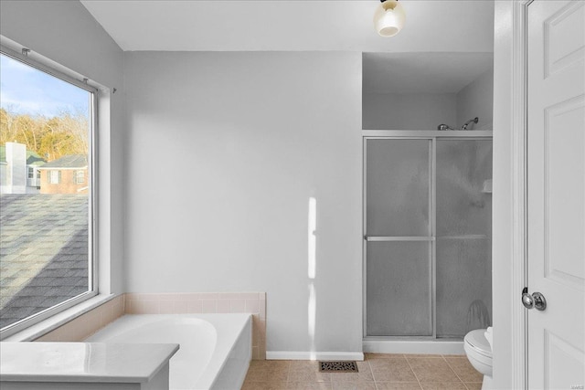 bathroom featuring a bath, a stall shower, tile patterned flooring, and toilet