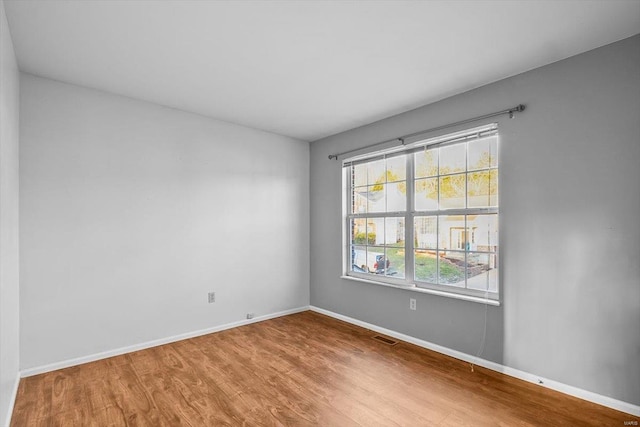 unfurnished room featuring wood finished floors, visible vents, and baseboards