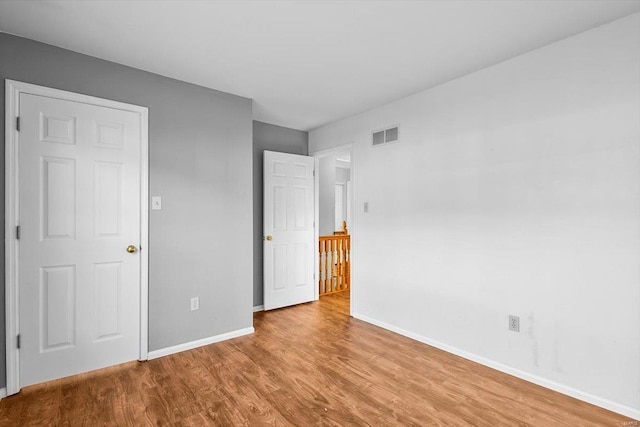 unfurnished bedroom with baseboards, visible vents, and wood finished floors