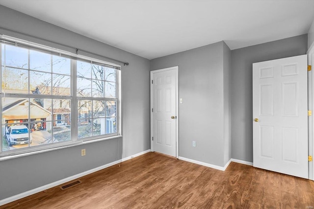 unfurnished bedroom featuring visible vents, baseboards, and wood finished floors