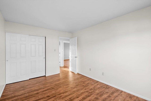 unfurnished bedroom featuring a closet, baseboards, and wood finished floors