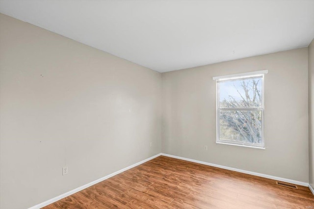 spare room featuring visible vents, baseboards, and wood finished floors