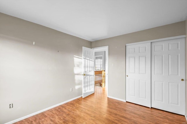 unfurnished bedroom with a closet, wood finished floors, and baseboards