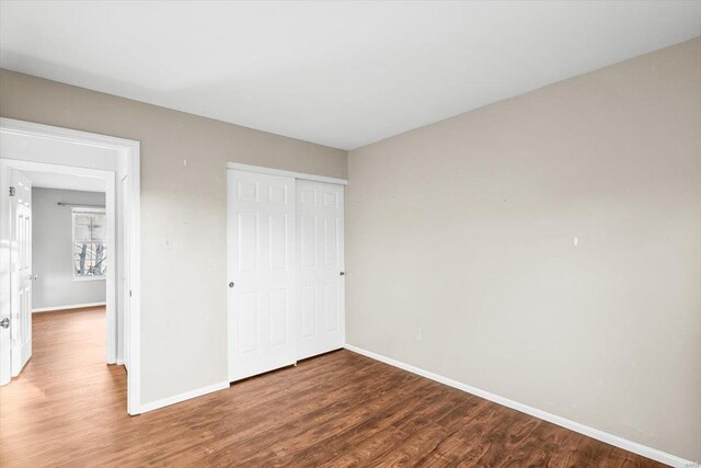 unfurnished bedroom with a closet, baseboards, and wood finished floors