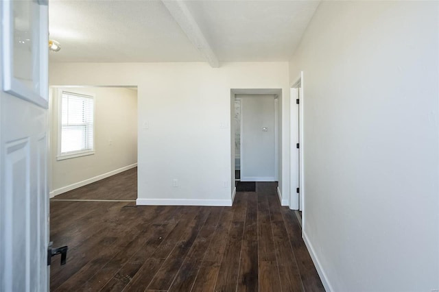 empty room featuring baseboards, dark wood-style flooring, and beamed ceiling