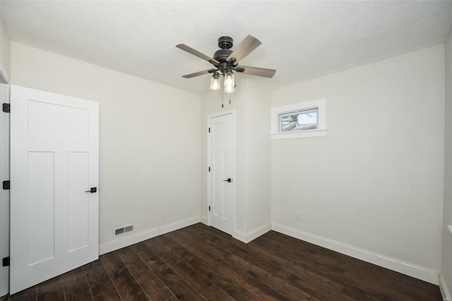 unfurnished room featuring a ceiling fan, dark wood finished floors, visible vents, and baseboards