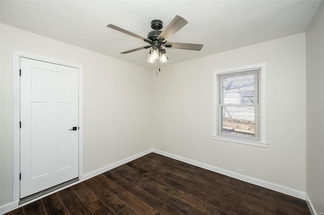 spare room with a ceiling fan, baseboards, and dark wood-style flooring