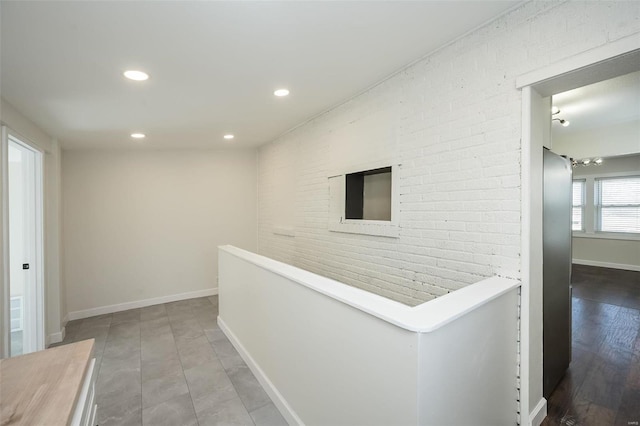 hallway featuring brick wall, recessed lighting, an upstairs landing, and baseboards