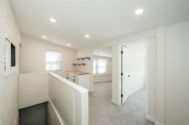 corridor with recessed lighting, baseboards, vaulted ceiling, and an upstairs landing