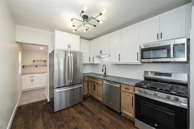 kitchen featuring baseboards, decorative backsplash, dark wood-style floors, appliances with stainless steel finishes, and a sink