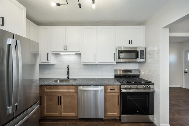 kitchen featuring tasteful backsplash, dark wood-style floors, appliances with stainless steel finishes, white cabinetry, and a sink