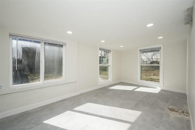 spare room with recessed lighting and baseboards