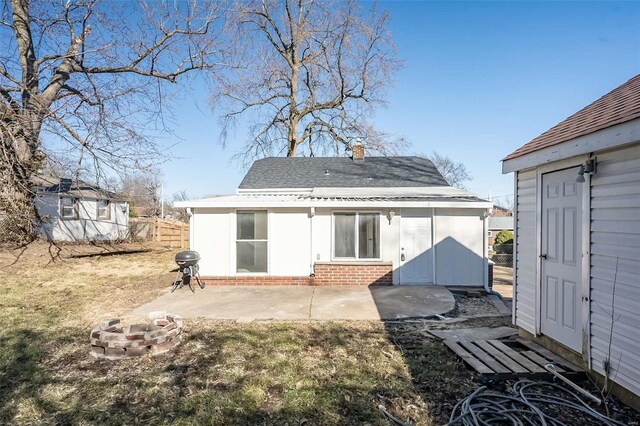 back of property with a chimney, a patio area, brick siding, and a fire pit