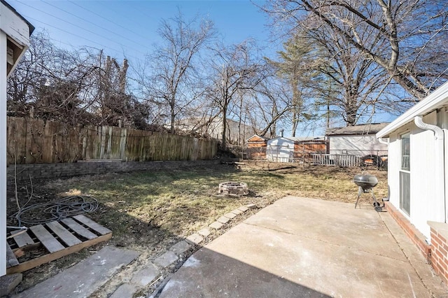 view of yard with an outbuilding, a patio, an outdoor fire pit, a fenced backyard, and a shed