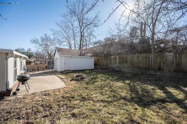 view of yard featuring an outdoor fire pit, a fenced backyard, a patio, and an outbuilding