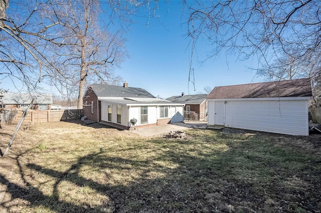 back of property featuring an outdoor fire pit, a fenced backyard, brick siding, an outdoor structure, and a lawn