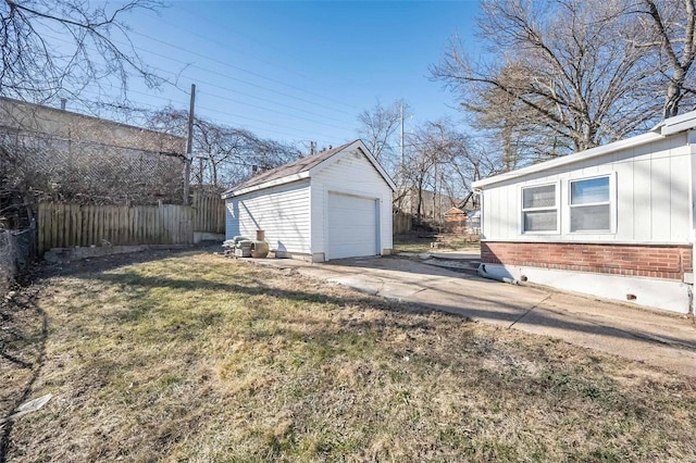 view of yard featuring driveway, a detached garage, fence, and an outbuilding