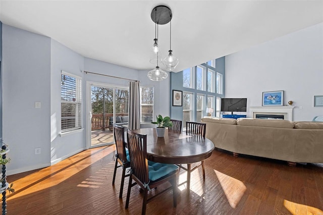 dining area with a fireplace, baseboards, and wood finished floors