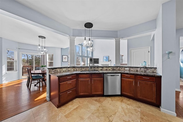 kitchen featuring stainless steel dishwasher, an inviting chandelier, a sink, and ornate columns