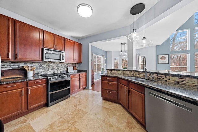 kitchen featuring dark stone countertops, stainless steel appliances, backsplash, and decorative light fixtures