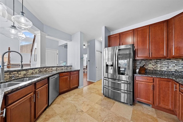 kitchen with dark stone countertops, decorative backsplash, stainless steel appliances, and a sink