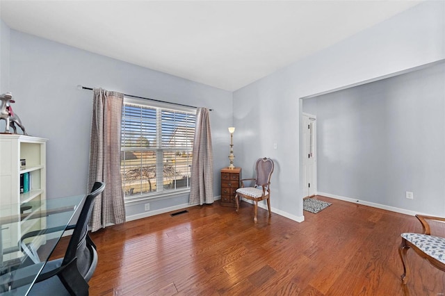 office space featuring baseboards, visible vents, and wood finished floors