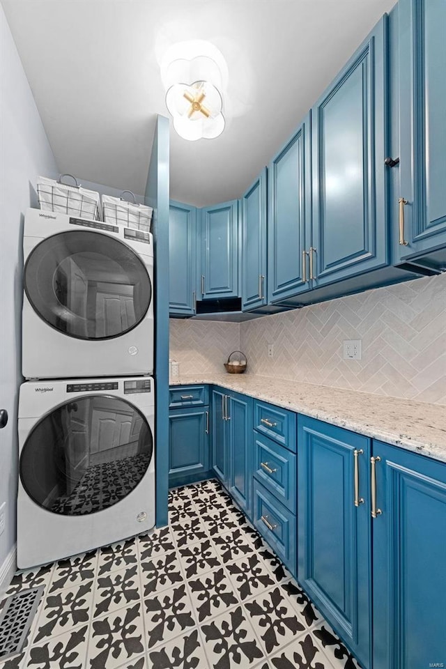 laundry room with cabinet space and stacked washer and clothes dryer