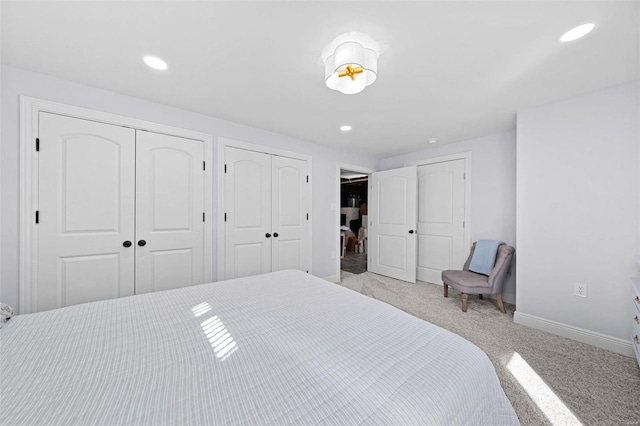 bedroom with light carpet, recessed lighting, baseboards, and multiple closets