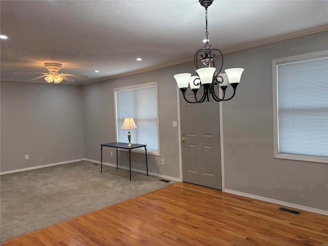 interior space featuring hardwood / wood-style flooring, ornamental molding, and ceiling fan with notable chandelier