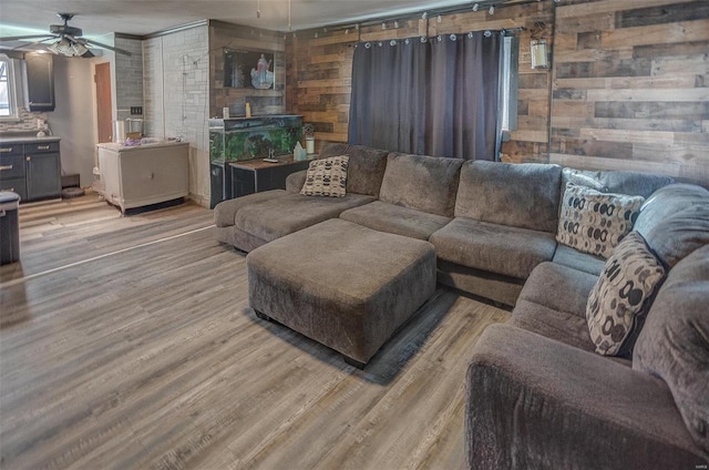 living room with wooden walls, light wood-type flooring, and ceiling fan